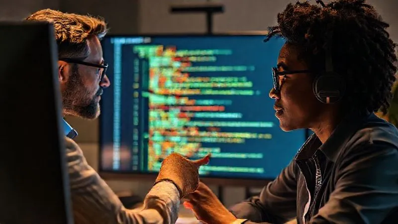 A photorealistic image of two diverse professionals on a video call, one sharing their screen showing lines of code with syntax highlighting, while the other intently listens and points at the screen. The atmosphere is collaborative and focused. Cinematic lighting, sharp focus on the screen and faces, depth of field blurring the background, 8K hyper-detailed, professional photography.