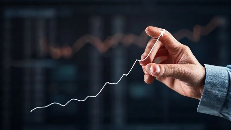 Photorealistic image depicting a financial graph with a clear upward trend, starting from a low point and rising steadily. A hand is drawing the line, symbolizing growth and recovery. Professional photography, 8K, cinematic lighting, sharp focus on the graph, depth of field blurring the background. Shot on a high-end DSLR.
